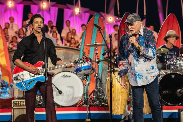 John Stamos and Mike Love of The Beach Boys perform together at a concert.