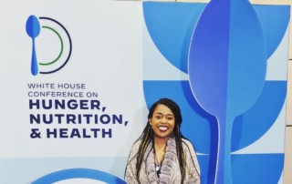 Tori Overton poses in front of a banner at the White House Conference of Hunger, Nutrition and Health.